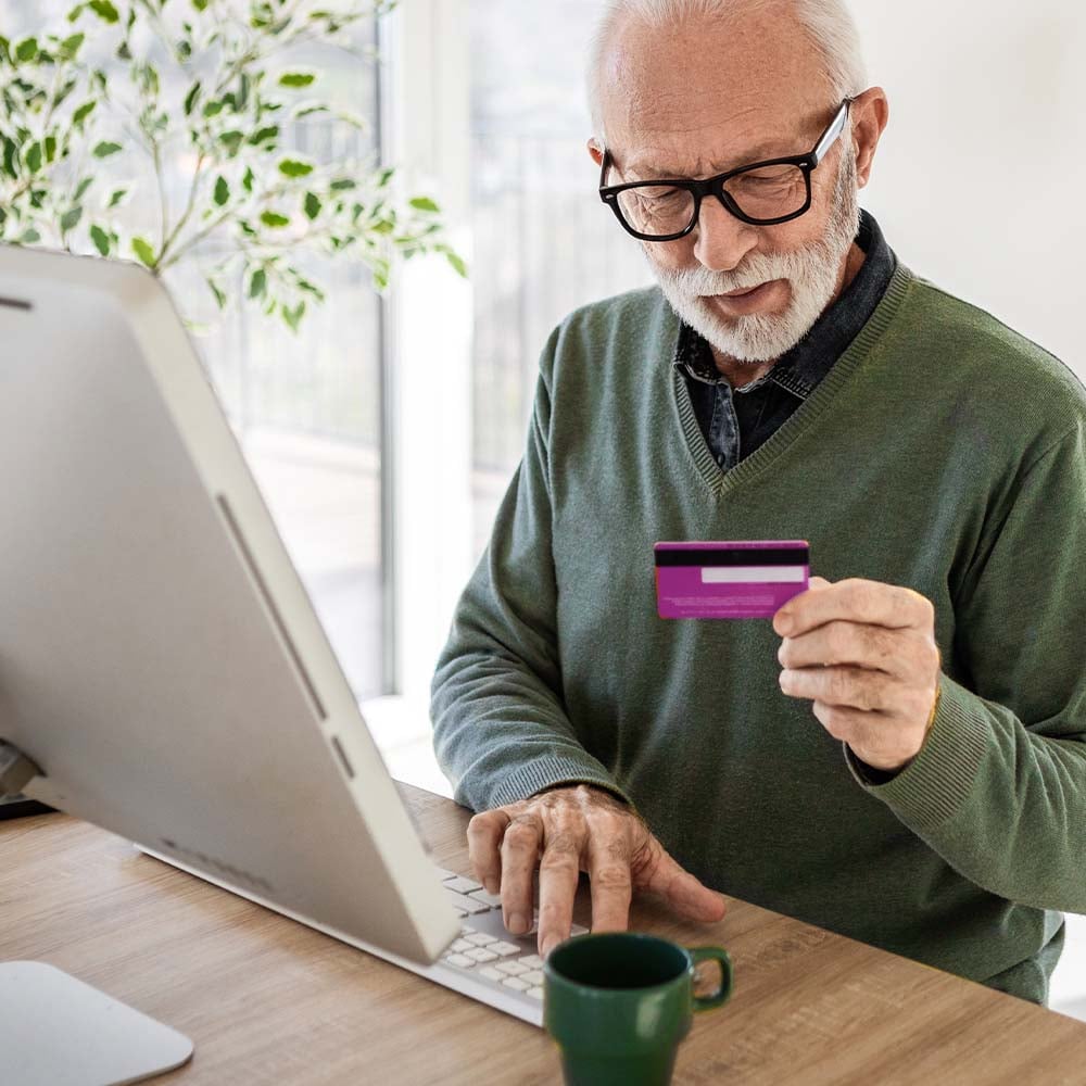 Man typing credit card number into a computer to make a purchase