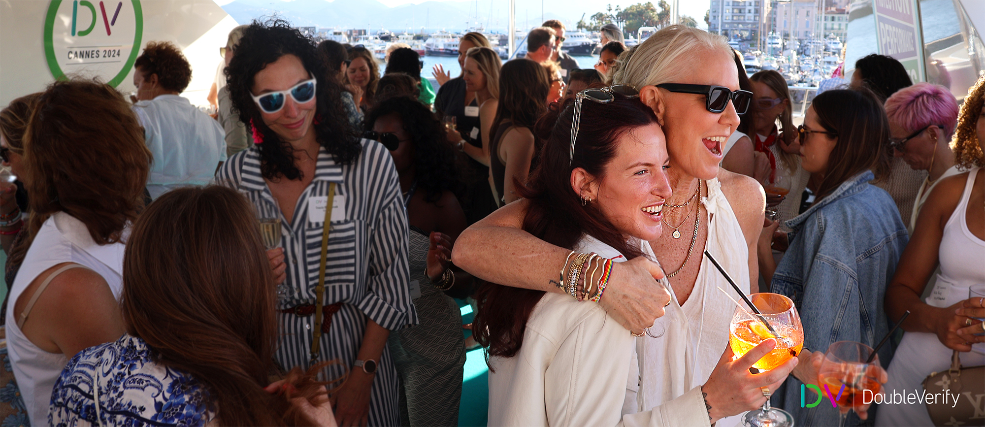 Photo taken on DV's yacht at the 2024 Cannes Lions International Festival of Creativity showing women socializing with a focus on two women laughing and embracing.