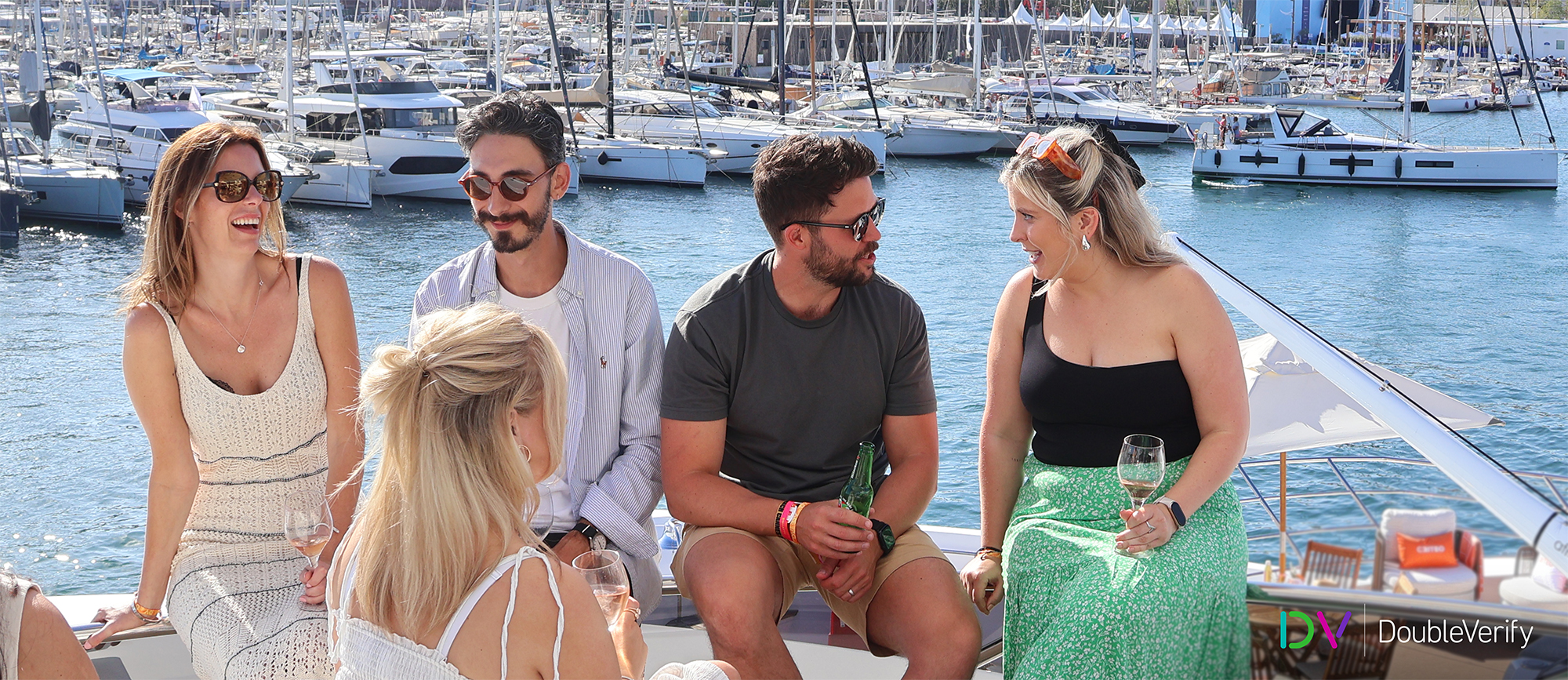 Photo taken on DV's yacht at the 2024 Cannes Lions International Festival of Creativity showing four people sitting on the edge of the yacht and socializing with drinks in their hands.